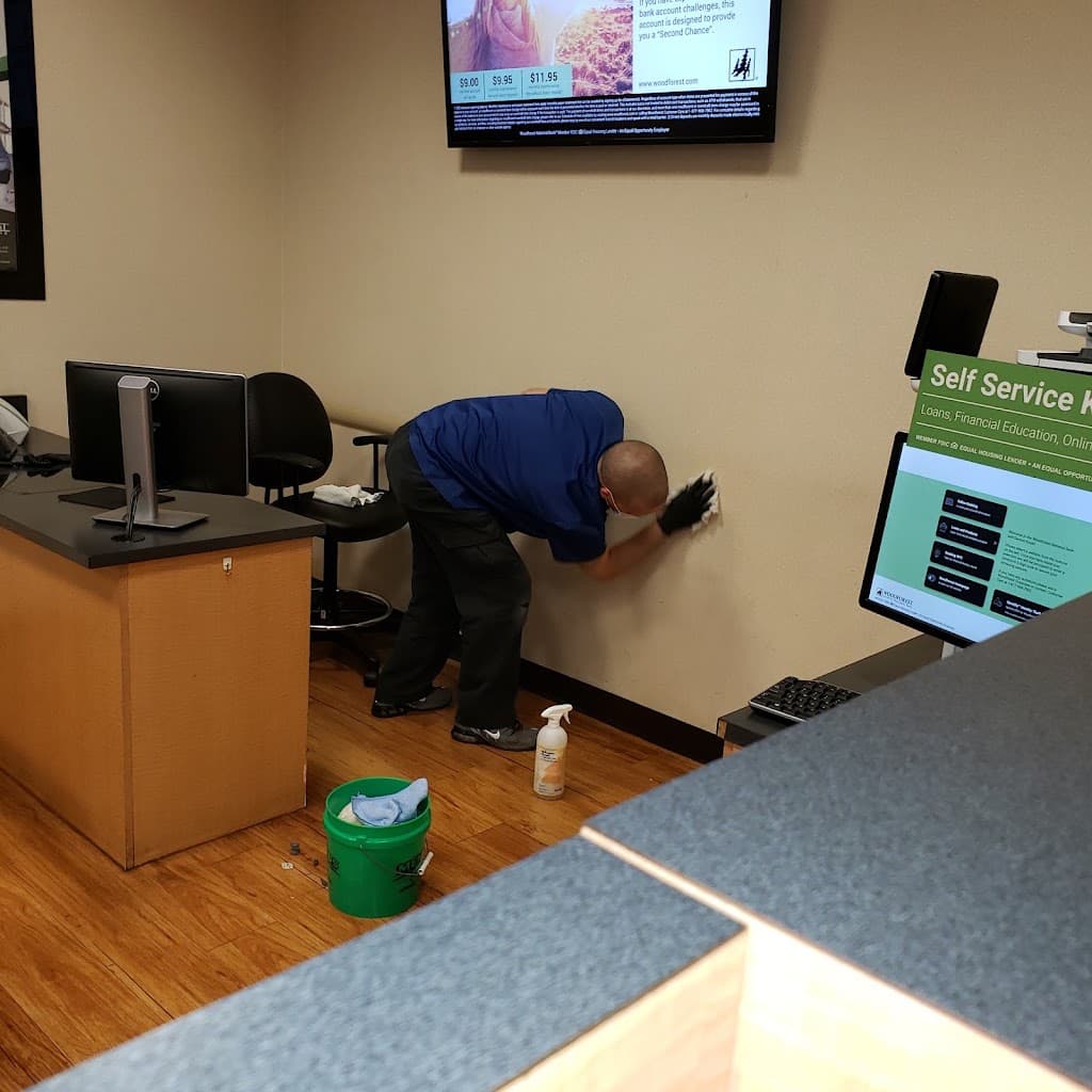 Elite Cleaning technician wiping down a wall behind a bank teller desk